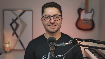 Guilherme Lima no estúdio, com microfone, guitarra e teclado