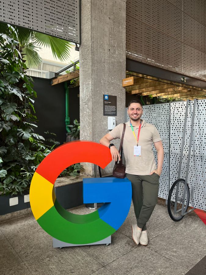 Guilherme Lima ao lado do logo gigante do Google no Google for Startups